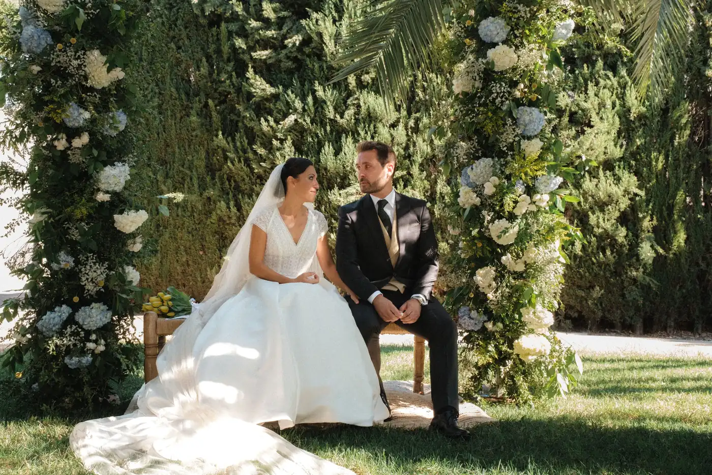 Wedding photographer Barcelona — couple under a floral ceremony arch in a Mediterranean garden by iArtist Studios